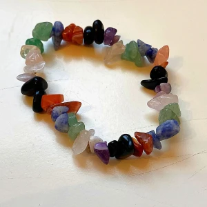 Färgglatt armband med stenar - Armband med oregelbundna pärlor i olika färger som svart, grön, blå, lila, rosa och orange. Pärlorna är av sten och sitter på elastisk tråd. Perfekt för dig som gillar boho vibes och vill ha något unikt på handleden.
