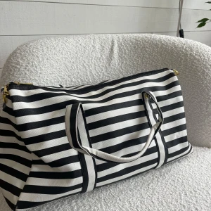 Väska🤍 - Stor och rymlig väska i svartvitt randigt skin marerial. Guldetaljer samt fack med dragkedja innuti. Snygg och stilren design