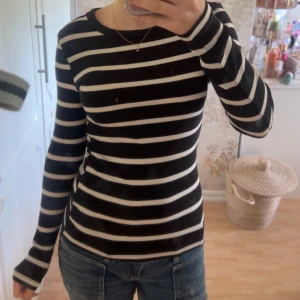 Svartvit randig långärmad tröja - Säljer en svart och vit randig långärmad tröja med rund hals. Tröjan har en slim passform och är perfekt att styla med jeans eller kjol. Mjukt material som känns skönt mot huden och passar året runt.