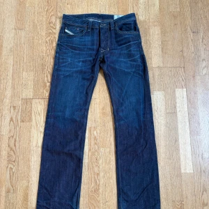 Diesel Larkee raka jeans blå - Snygga mörkblå jeans från Diesel, modell Larkee. Klassisk rak passform med regular-straight ben och fem fickor. Jeansen har kontrastsömmar och är tillverkade i slitstarkt denim. Perfekta för dig som gillar en tidlös och clean look.