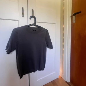 Grå kortärmad tröja  - En stilren mörkgrå tröja från Lindex i storlek XS. Perfekt för dig som gillar en enkel och clean look💖.