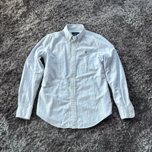 Randig skjorta från Ralph Lauren M - Snygg ljusblå och vit randig skjorta från Ralph Lauren i custom fit. Klassisk button-down krage, broderad logga på bröstet och långa ärmar. Tillverkad i mjuk bomull och perfekt för en clean och stilren look. Skriv om du har några frågor 🙏🏻