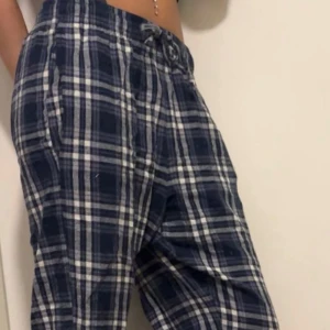 Rutiga blå-vita pyjamasbyxor - Säljer ett par blå och vita rutiga pyjamasbyxor med snörning i midjan. Byxorna har en loose fit och är perfekta för chill dagar. Storlek M-S