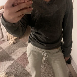 Mörkgrå V-ringad tröja Esprit - Mörkgrå V-ringad tröja från Esprit med ribbade muddar och nederkant. Enkel och stilren design som funkar till det mesta. Skön passform och mjukt material, perfekt för lager-på-lager under höst och vinter.