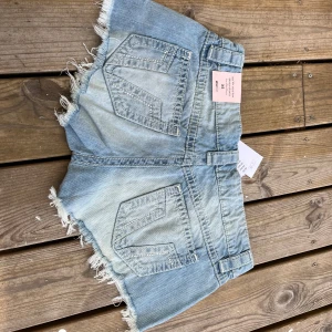 Ljusblå slitna jeansshorts Gina Tricot XS - HELT NYA JEANSSHORTS MED LAPPAR KVAR. Slutsålda på nätet.                      Snygga ljusblå jeansshorts från Gina tricot med slitna detaljer och fransig kant. Klassisk femficksmodell med låg midja och dragkedja. Perfekta för sommaren när du vill ha en chill och trendig look.