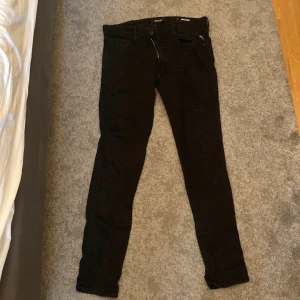Svarta Replay Anbass jeans slim fit - Svarta Replay Anbass jeans i slim fit med klassisk femficksdesign och snygga detaljer. Jeansen har en smal passform och är tillverkade i stretchigt denim för extra komfort. Längden är 34 så du som är 190 plus har 32 i bredd storlek tveka inte på att höra av dig.