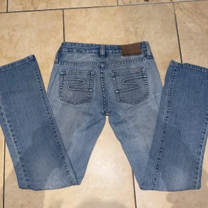 Lågmidjade jeans - Säljer ett par as snygga vintag lågmidjade bootcut jeans i en ganska ljusblå färg som tyvärr är lite små på mig, vid frågor kontakta mig💕 Midjemåttet: 36/37 cm rakt över  Innerbenslängd: 82 cm Skulle säga är w26 och L32 Använd gärna köp nu funktionen. Jag köpte för 600kr men säljer billigare. Vid snabb affär kan priset diskuteras💕