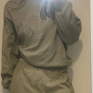 Sage green mjukisset med tryck - Sage green mjukis set (baby grön färg)  Mjukisbyxorna har snören inuti den som du kan justera storleken med.  Tjocktröjan har ett tryck på med badmintonfjäderbollar med text Retro collage motiv.  Tröjans lapp är bortklippt med är runt storlek S-M baggy i storken. Byxorna är baggy i storleken och har XS.