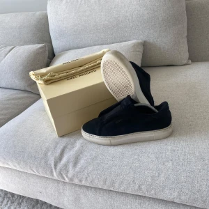 Svarta sneakers från Axel Arigato - Stilrena svarta sneakers från Axel Arigato i mocka med vit platt sula. Allt är bra bara att en liten tråd som har släppt (inget som påverkar eller kommer bli större) pris kan diskuteras 