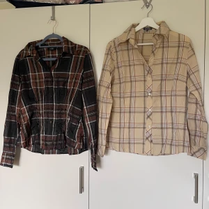 Två rutiga skjortor i brunt och beige - Två långärmade skjortor med rutigt mönster. Ena skjortan är mörkbrun och svart med inslag av vitt och orange, från esble. Den andra är beige med bruna och röda rutor, från Street One. Båda har klassisk krage och knäppning framtill. Perfekta för en avslappnad och trendig look.