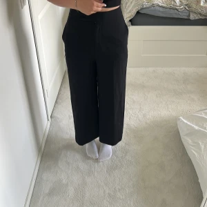 Svarta vida kostymbyxor från Zara XS - Snygga svarta kostymbyxor från Zara i storlek XS. Byxorna är högmidjade med croppad längd och har en vid passform som ger en trendig siluett. Perfekta att styla med sneakers eller boots för en clean look.