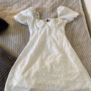 Vit blommig kortklänning H&M Divided - Supersöt vit kortklänning med ljusblått blommönster från H&M Divided. Använd 1 gång🩷storlek s🩷