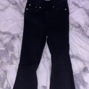 Svarta bootcut jeans med utsvängda ben - Säljer ett par svarta jeans bootcut och breda ben. Materialet är lite hårt och färgen är helsvart.