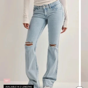 Ljusblå bootcut jeans med slitningar - Snygga ljusblå jeans med bootcut passform och slitna knän. Jeansen har klassiska fem fickor och coola broderade detaljer på bakfickorna. Tillverkade i mjukt denimtyg som ger en skön känsla och avslappnad look.