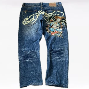 Ed hardy jeans - Ett par as feta ed Hardy jeans. Ganska baggy. Fet bordering och storlek 38 i midjan. Från 2008. (Midja 51 cm) (ben öppning 24cm) (längd 100cm)