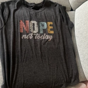 Svart t-shirt med färgglatt tryck - Cool svart t-shirt med texten 'NOPE not today' i stora, färgglada bokstäver på bröstet. T-shirten har korta ärmar och en avslappnad passform. Perfekt för dig som vill ha en chill och skön stil.