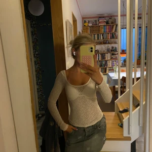 Vit spetsig långärmad topp - Säljer en superfin vit långärmad topp i spets med djup urringning både fram och bak. Tight passform som sitter snyggt! Skulle rekommendera annan bh! Skitsnygg.