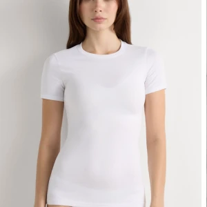 Intimissimi vit kortärmad tröja i Superior-bomullsstretch  - Enkel och stilren vit t-shirt med rund hals och korta ärmar. Sitter tajt mot kroppen och är gjord i mjuk bomull, perfekt att matcha med jeans eller shorts. Klassisk modell utan tryck eller mönster.