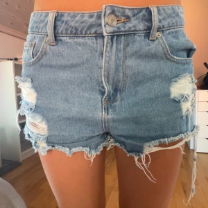 Rippade jeansshorts från We Are Denim - Snygga ljusblå jeansshorts från We Are Denim med rejält slitna detaljer och fransig kant. Klassisk femficksmodell med hög midja och  hål framtill och baktill. 