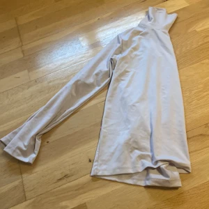 Ljusgrå polotröja från CRW - Säljer en stilren ljusgrå polotröja från CRW med lång ärm och hög krage. Perfekt att ha som lager under jackan eller till ett par snygga jeans. Tröjan är i ett mjukt och stretchigt syntetmaterial som känns skönt mot huden.