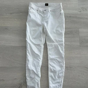 Vita skinny jeans från Lee - Snygga vita jeans från Lee i skinny fit med klassisk femficksdesign och dragkedjegylf. Byxorna har låg midja och är tillverkade i bomull med lite stretch för en bekväm passform. Perfekta för dig som gillar en clean och fräsch look.