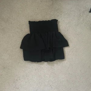 Svart volangkjol  - Supersnygg svart kortkjol med volangdetalj. Perfekt för dig som vill ha en clean look men de är även elegant