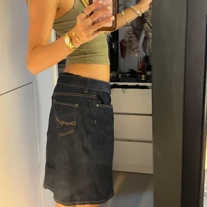 Mörk jeanskjol Tommy Hilfiger - Säljer en mörkblå jeanskjol från Tommy Hilfiger, modell Rome Regular Fit. Kjolen har klassiska fickor fram och bak, snygga kontrastsömmar och knapp med TH-logga. Perfekt till sneakers eller boots för en chill look.