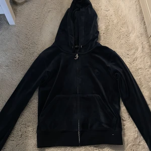 Mörkblå velour hoodie Juicy Couture XS - Säljer en klassisk mörkblå hoodie från Juicy Couture i mjuk velour. Tröjan har huva, dragkedja framtill och känguruficka. Perfekt för en chill och trendig look. Ikonisk JC-detalj på dragkedjan och diskret logga på bröstet. Har inte använt på ett bra tag.