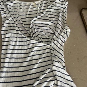 Randig omlottopp från H&M Basics - Säljer en vit omlottopp med marinblå ränder från H&M Basics. Toppen har v-ringning. För endast 30kr 