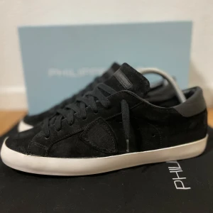 Svarta sneakers från Philippe Model - Stilrena svarta sneakers från Philippe Model i mocka med vita sulor. Skorna har rund tå, svarta snören och diskret logotyp på sidan. Perfekta för dig som gillar en clean och klassisk look med premiumkänsla. Skorna är i mycket bra skick! Storlek 42. Endast dustbag medföljer. Nypriset ligger runt 3500 kr! Hör av er ifall ni har några frågor! 🙌