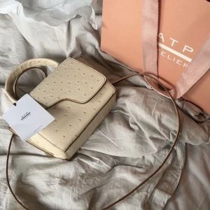Beige handväska från ATP Atelier - Superfin beige axelremsväska från ATP Atelier, med lite bruna detaljer på kanterna. Väskan är som ny och knappt kommit till användning💕Ser ut som att modellen utgått från hemsidan!