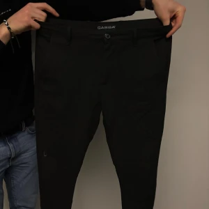 Mörkgrå chinos från Gabba - Säljer ett par stilrena mörkgrå chinos från Gabba. Byxorna har en klassisk design med knapp och dragkedja framtill. Perfekta för en snygg och avslappnad look.