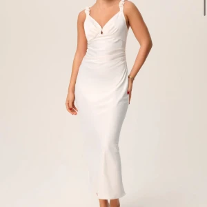 Adoore klänning - Elegant vit långklänning från Adoore i storlek 40 i modellen ”Nimes slip dress”. Klänningen har en figurnära passform som framhäver silhuetten. Perfekt för speciella tillfällen. Helt ny med lapp kvar.