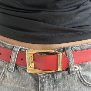 Rött bälte med guldfärgat spänne - Snyggt rött bälte med ett stort guldfärgat spänne. Köpt på sellpy men väldigt bra skick! Säljer pga för liten storlek. 