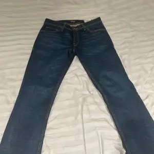 Säljer ett par klassiska blå jeans från Jack & Jones. De har en normal passform och är tillverkade i denim med snygga kontrastsömmar. Perfekta för en avslappnad stil.