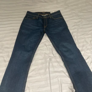 Blå jeans från Jack & Jones - Säljer ett par klassiska blå jeans från Jack & Jones. De har en normal passform och är tillverkade i denim med snygga kontrastsömmar. Perfekta för en avslappnad stil.
