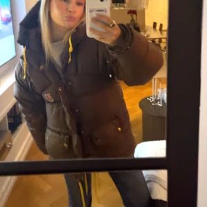 Brun dunjacka från Fjällräven - Säljer min bruna fjällräven som jag ej vill ha längre❤️ storlek xxxs och sitter jätte fint, tvättar den 1 gång och funka jätte bra❤️ !!obssss har satt dit gula snören vid luvan då de åkte av i tvätten. skriv för mer bilder eller funderingar❤️bra skick 