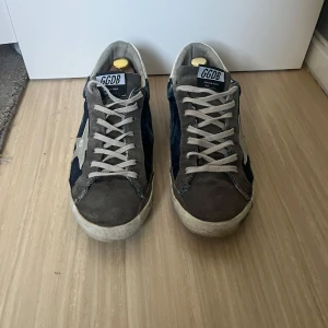 Skor från golden goose - Snygga sneakers från golden goose i en kombination av grått och blått med en vit stjärndetalj på sidan. Skorna har snörning och en klassisk design som passar perfekt för en avslappnad stil. Inga deffekter och storleken är 43
