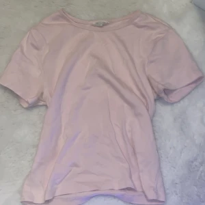 Ljusrosa t-shirt från Gina Tricot - Säljer en ljusrosa t-shirt från Gina Tricot. Den har en enkel design med korta ärmar och rund halsringning. Fin med t ex pärlor och halsband! Är i storlek L men är enligt mig rätt så liten i storlek💗