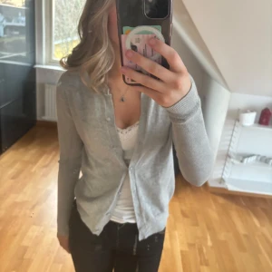 Grå kofta från Zara - Säljer en stilren grå kofta från Zara. Den har en klassisk design med knappar framtill och långa ärmar. Perfekt för lager-på-lager och passar till många olika outfits.