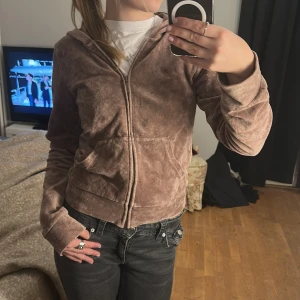 Brun velour hoodie - Säljer en mysig brun velour hoodie med dragkedja och huva. Perfekt för en avslappnad stil. Den har långa ärmar och en bekväm passform.