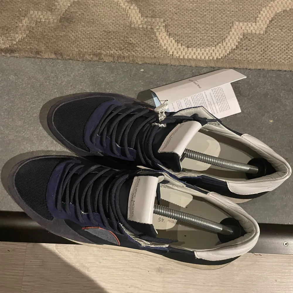 Skick 10/10 helt nya trainers i storlek 45 . Phillipe modell boxen samt tagsen och dustbag följer självklart med det vill säga allt OG. Snygga marinblå sneakers från Philippe Model med vita och svarta detaljer. Skorna har en broderad logga på sidan och snörning framtill. Perfekta för en stilren look.. Kengät.