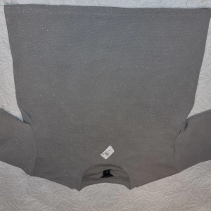 Grå glittrig tröja från H&M, st S-M - Snygg grå tröja från H&M med glittrande detaljer. Perfekt för att lägga till lite glamour i vardagen. Tröjan har långa ärmar och en klassisk rund halsringning, kan inte passa bättre till alla tillfällen