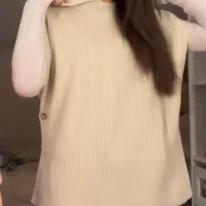 Beige stickad väst - Snygg beige stickad väst med knappar på sidan. Perfekt för lager-på-lager-stil och ger en mysig känsla. Passar bra till både vardag och mer uppklädda tillfällen.