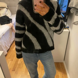 Svart och vit mohair tröja  - Säljer en snygg svart och vit polotröja i mohair, med ett coolt zebramönster. Tröjan har långa ärmar och en mysig polokrage, perfekt för kyliga dagar. Den är stickad och har en loose passform. Står strl XS, men skulle säga att strl S och passar lätt strl M☺️