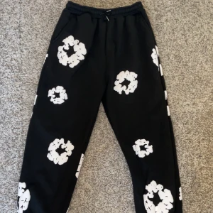 Svarta mjukisbyxor med vita mönster - Snygga svarta mjukisbyxor med unika vita mönster. Byxorna har en elastisk midja med snörning för extra komfort. Perfekta för en avslappnad stil. Storlek L. Average kvalite, inget jätte bra men bra för priset
