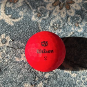 Röd golfboll från Wilson - Säljer en röd golfboll från Wilson med texten 'Wilson 2' och 'Ultra 500'. Perfekt för att synas på golfbanan. 🏌️‍♂️
