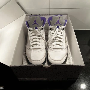 Nike Air Jordan 5 Retro Concord - Säljer ett par Air Jordan 5 Retro Concord i vitt med lila detaljer. Storlek 42, kartong och kvitto finns. Bra skick, det enda som finns att anmärka på är att det är lite avskavt på insidan i den vänstra skon, se sista bilden