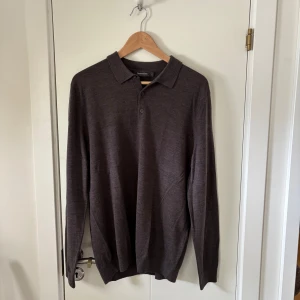 Stickad tröja - Säljer en stilren brun långärmad pikétröja från Dressmann i merinoull. Storlek L, inga defekter, bra skick, vid frågor och funderingar är det bara att höra av sig:) 