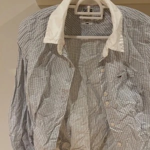 Rutig skjorta från Hilfiger Denim med vit krage - Säljer en klassisk rutig damskjorta från Hilfiger Denim i vitt och blått med kontrasterande vit krage. Skjortan har långa ärmar och knappar framtill. Perfekt för dig som gillar stilrena detaljer och tidlös design. Ostruken. Liten XS. 75:-